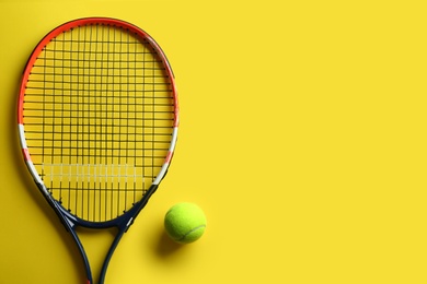 Photo of Tennis racket and ball on yellow background, flat lay. Space for text