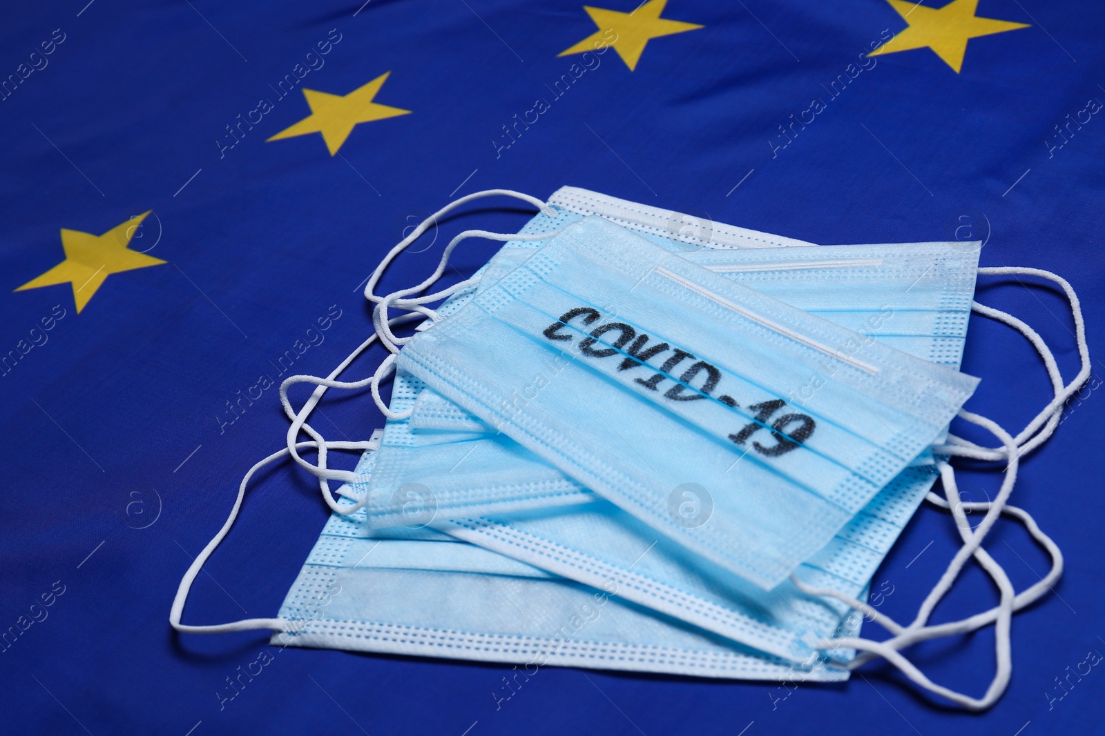 Photo of Medical masks with word COVID-19 on flag of European Union