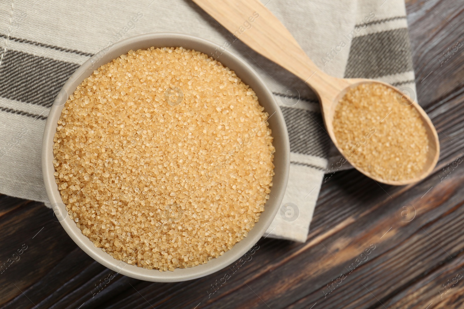 Photo of Brown sugar in bowl and spoon on wooden table, flat lay