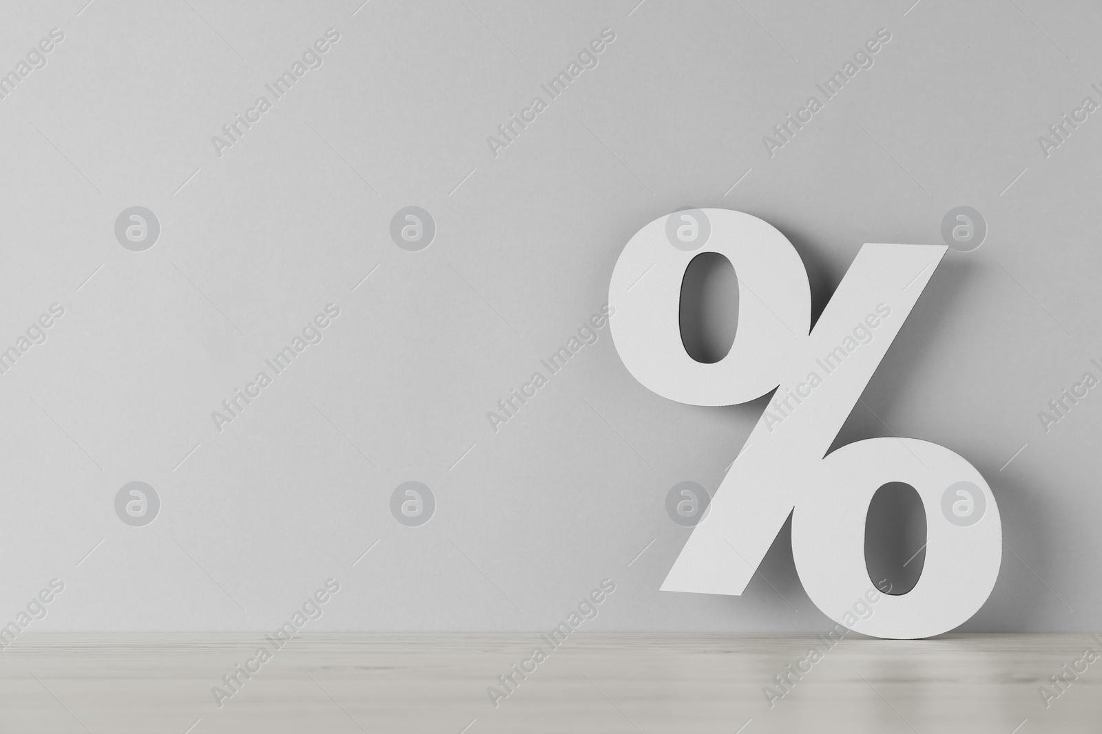 Photo of Paper percent symbol cutout on wooden table against light grey background. Space for text