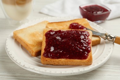 Photo of Toast with tasty raspberry jam and roasted slices of bread on white wooden table, closeup