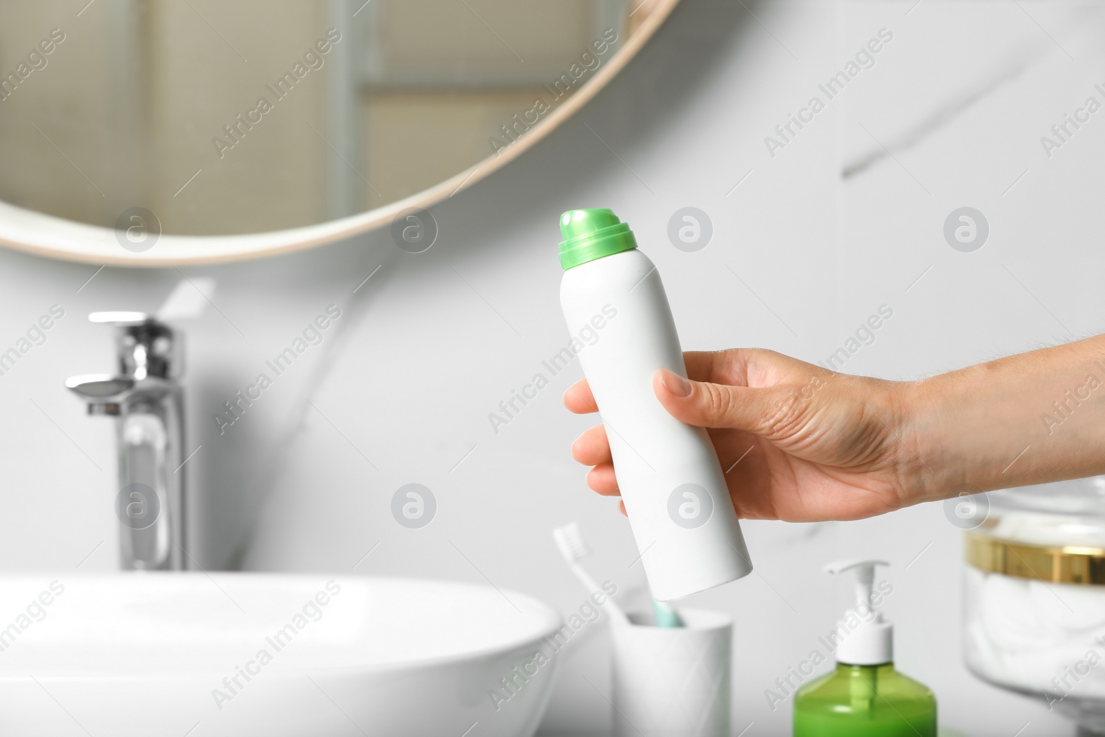 Photo of Woman holding deodorant in bathroom, closeup