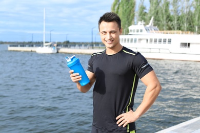 Man with bottle of protein shake near river