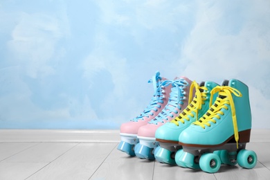 Photo of Vintage roller skates on floor near color wall. Space for text
