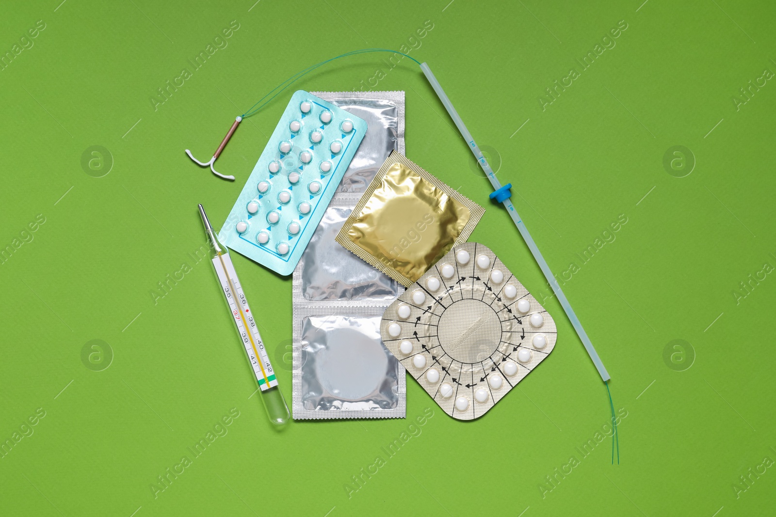 Photo of Contraceptive pills, condoms, intrauterine device and thermometer on light green background, flat lay. Different birth control methods