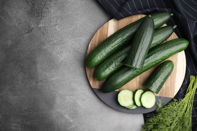 Fresh cucumbers and dill on grey textured table, top view. Space for text