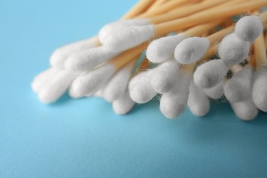Heap of clean cotton buds on light blue background, closeup