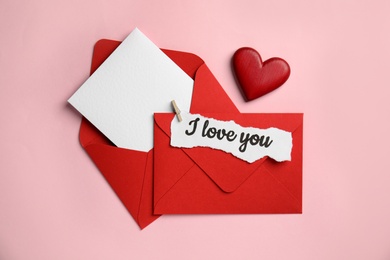 Photo of Sheet of paper with phrase I Love You, envelopes and decorative heart on pink background, flat lay