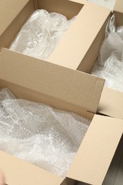 Photo of Many open cardboard boxes with bubble wrap on white floor