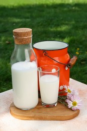 Photo of Tasty fresh milk on color textured table outdoors