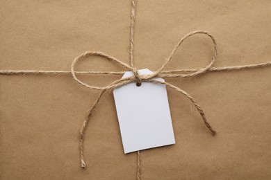 Photo of Parcel wrapped in kraft paper with tag as background, closeup