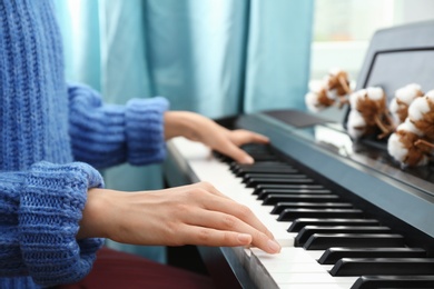 Photo of Young woman playing piano at home, closeup