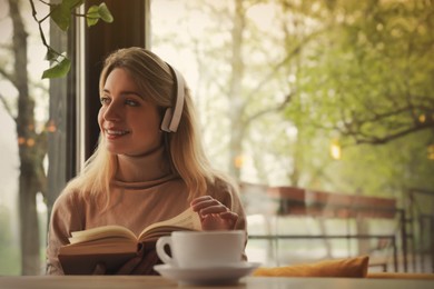 Woman listening to audiobook at table in cafe