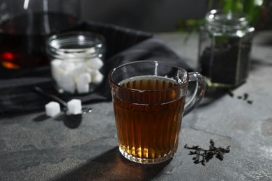 Photo of Tasty hot tea in cup on grey table, closeup