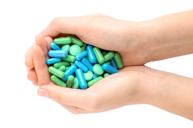 Woman holding color pills on white background, closeup