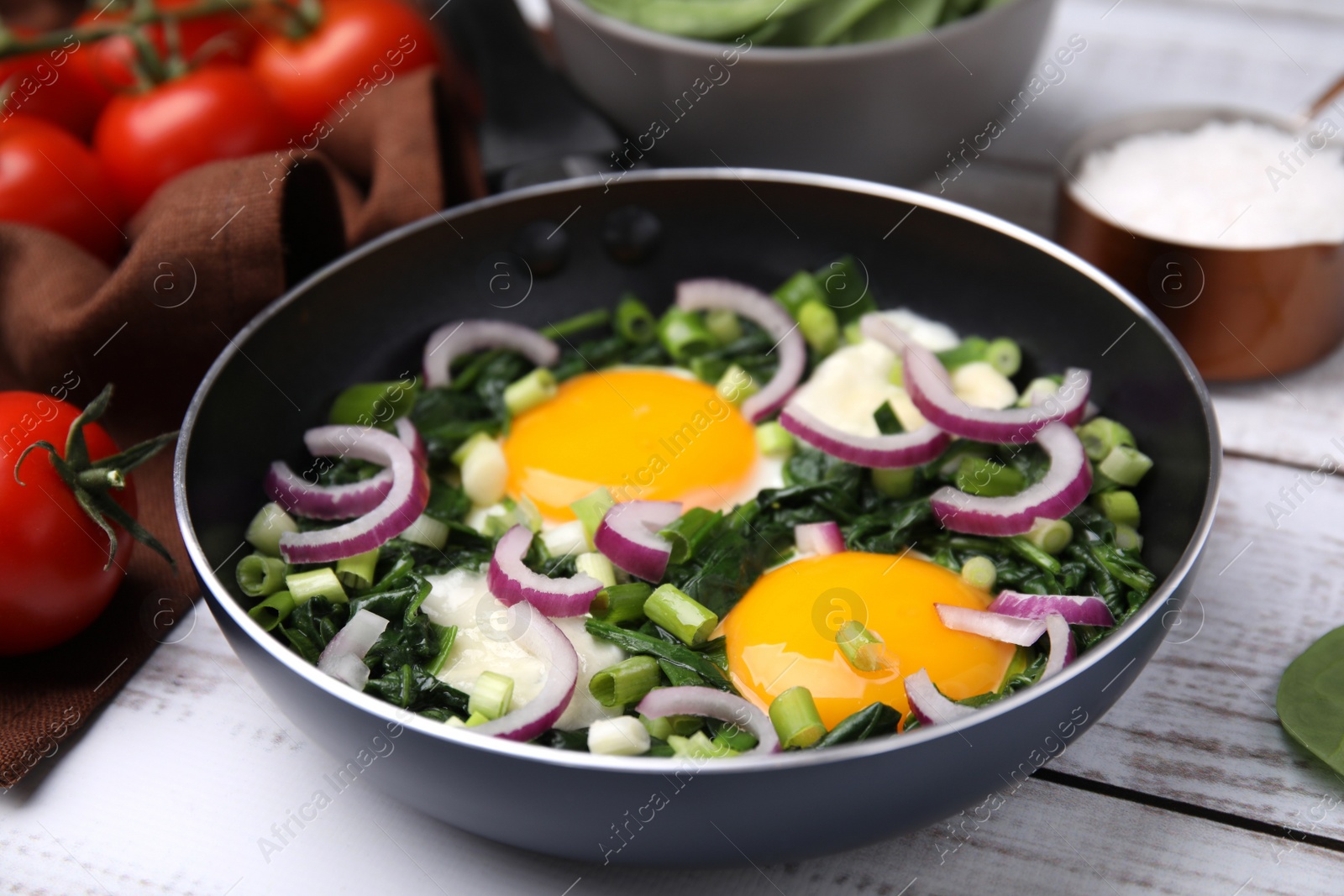 Photo of Tasty green Shakshouka served on white wooden table, closeup