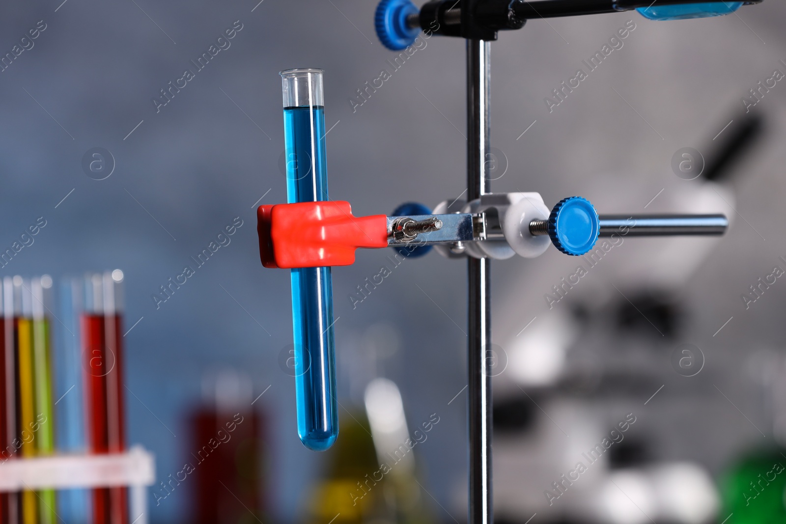 Photo of Test tube with blue liquid on retort stand in laboratory, closeup. Space for text