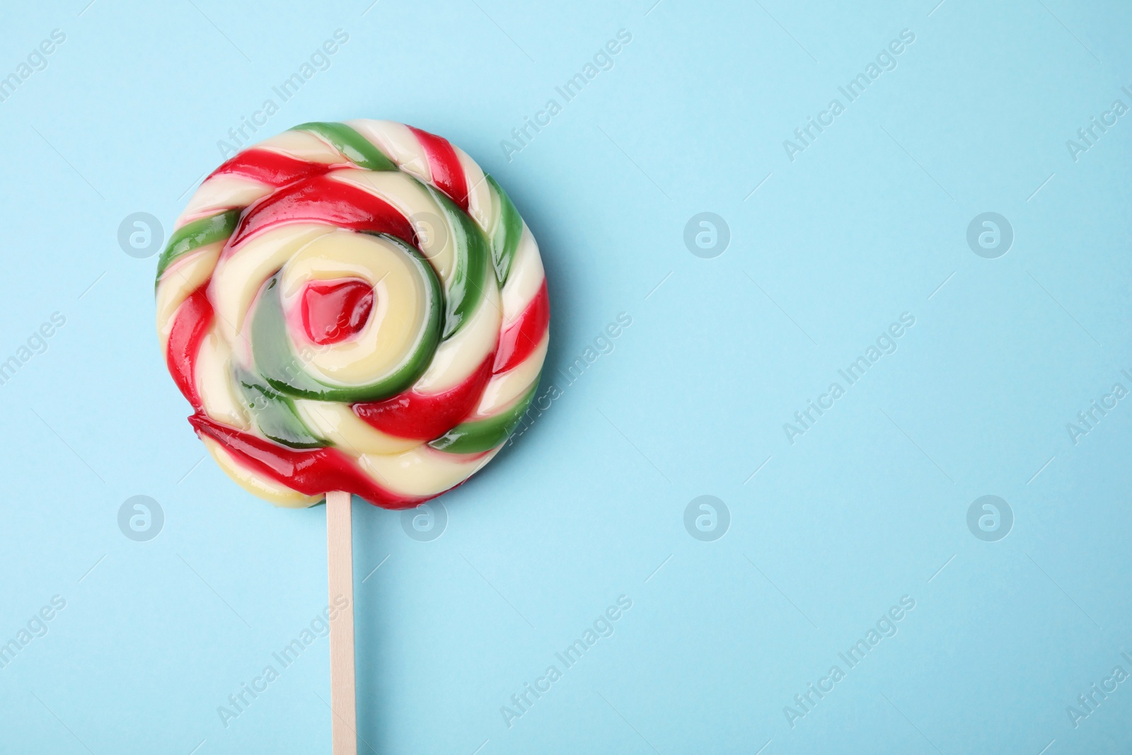 Photo of Colorful lollipop on light blue background, top view. Space for text