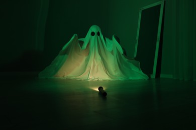 Photo of Creepy ghost. Woman covered with sheet in green light