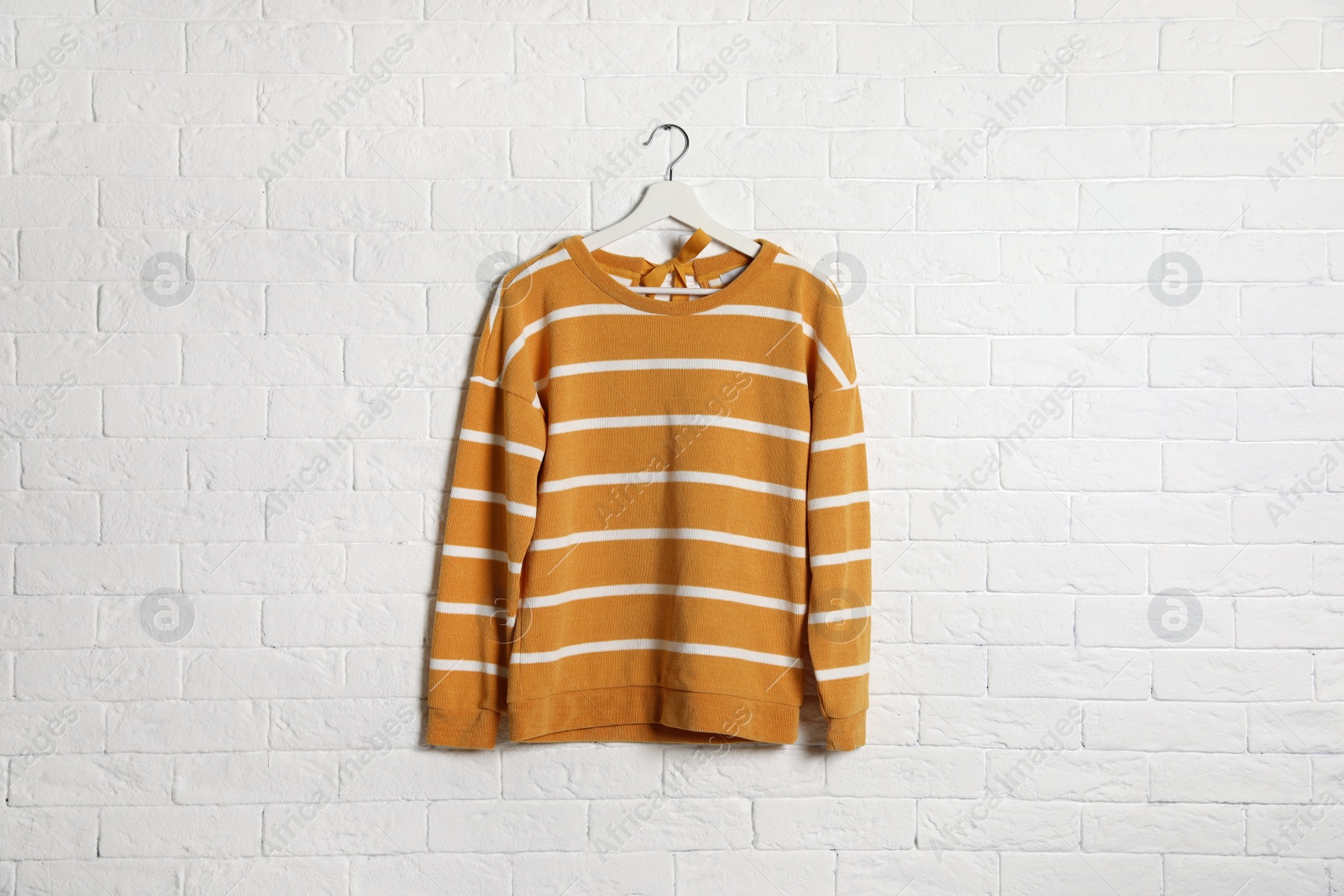 Photo of Hanger with stylish sweater on brick wall