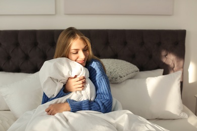 Beautiful young woman hugging soft blanket in bed at home. Winter atmosphere