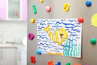 Photo of Child's drawing and magnets on refrigerator door in kitchen