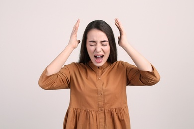 Portrait of stressed young woman on beige background