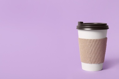 Takeaway paper coffee cup with cardboard sleeve on violet background. Space for text