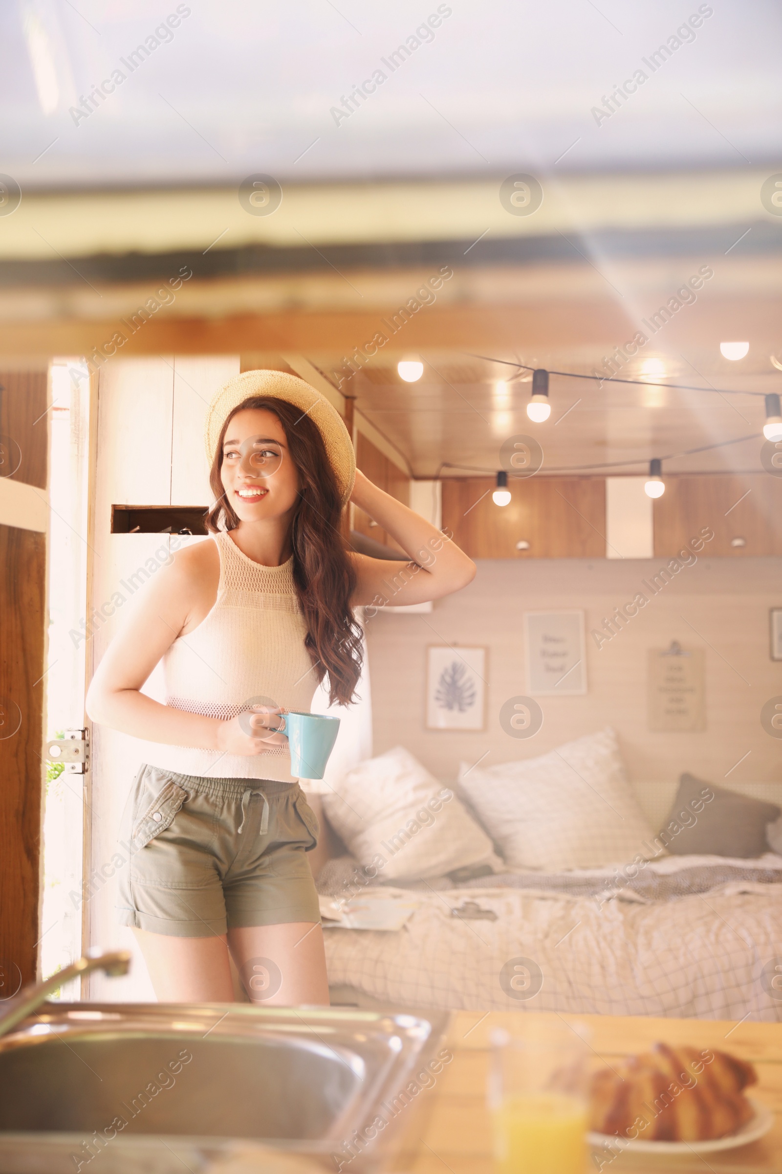 Photo of Young woman with cup in trailer, space for text. Camping vacation