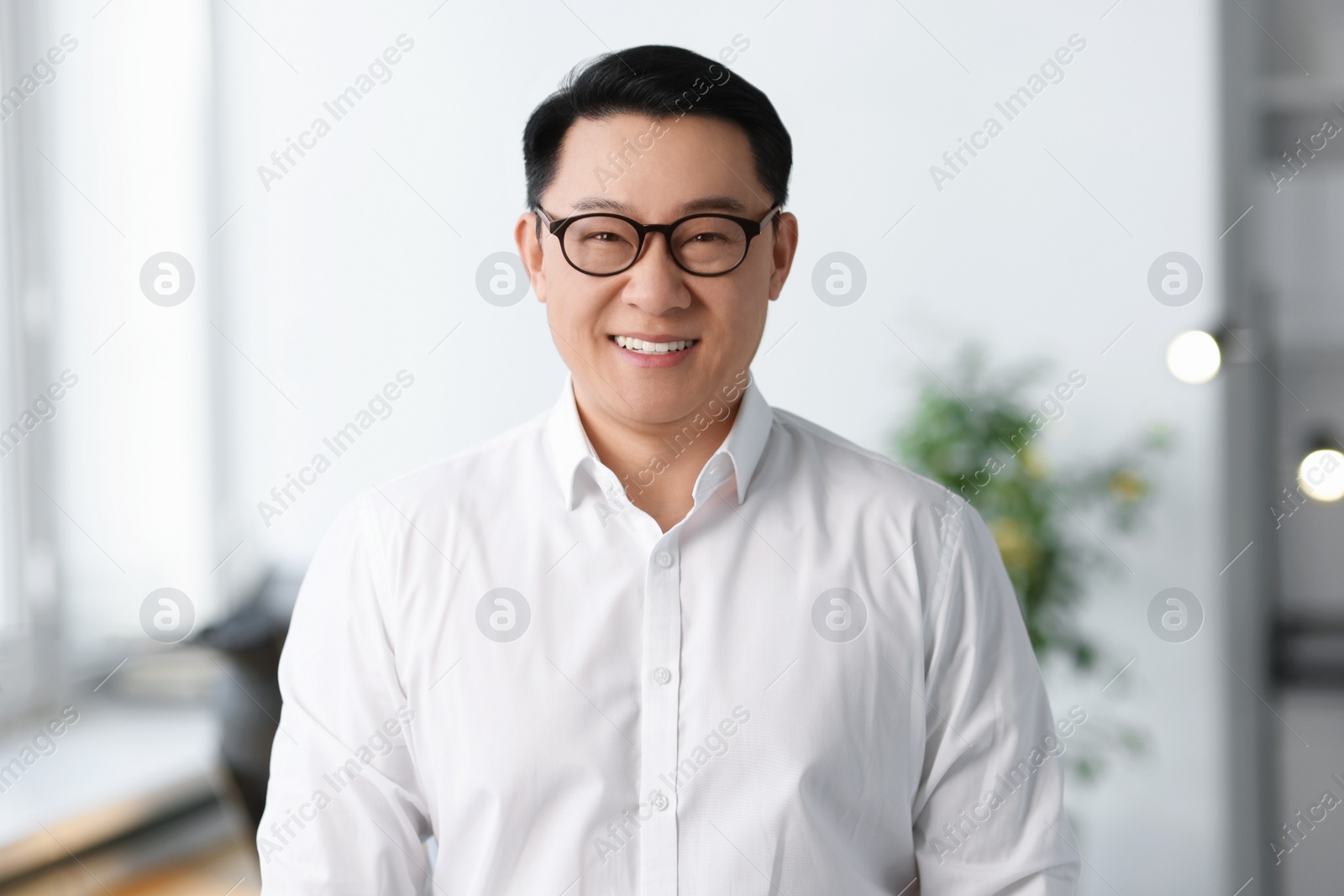 Photo of Portrait of smiling businessman in glasses indoors