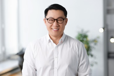 Portrait of smiling businessman in glasses indoors