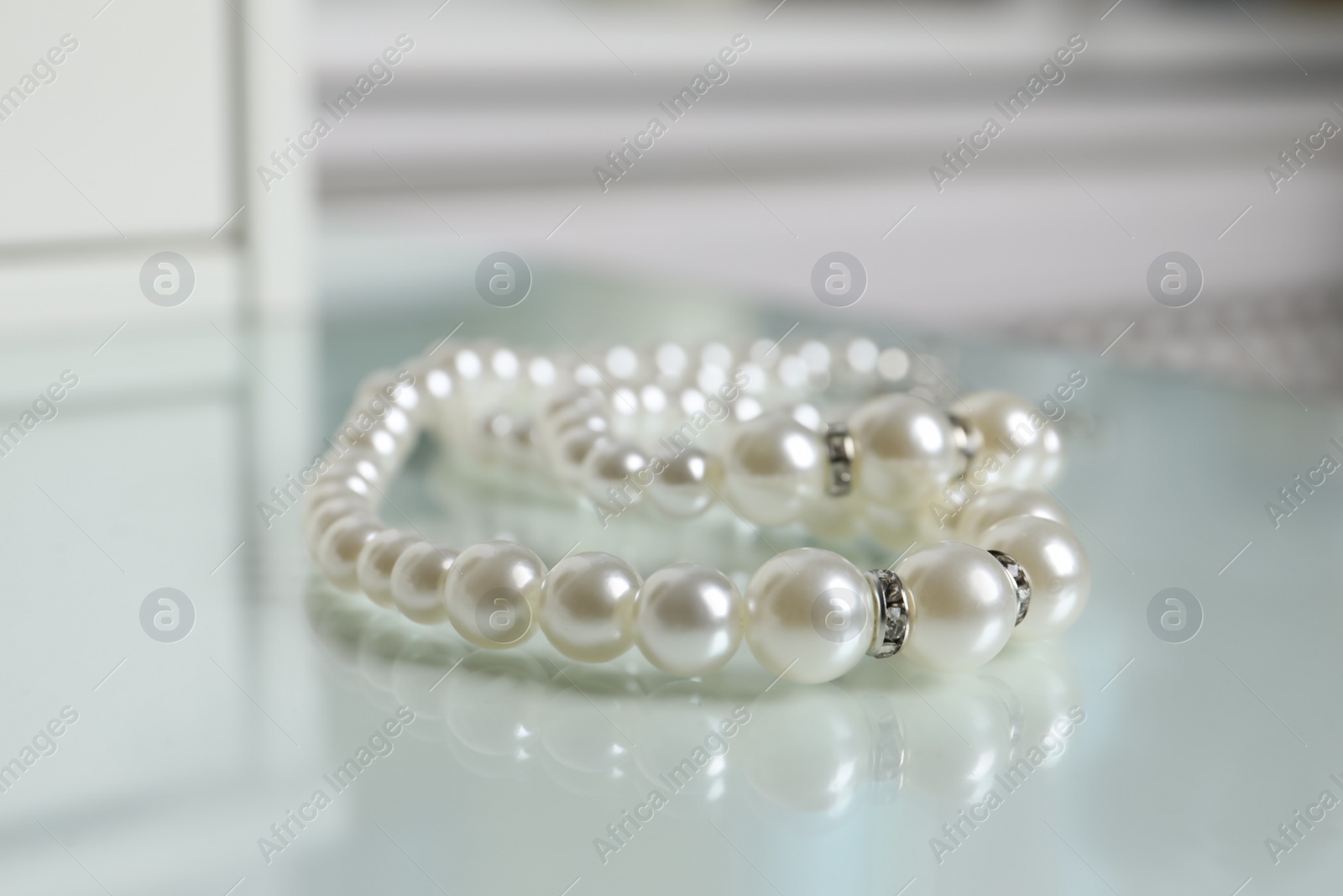 Photo of Elegant pearl necklace on white table, closeup