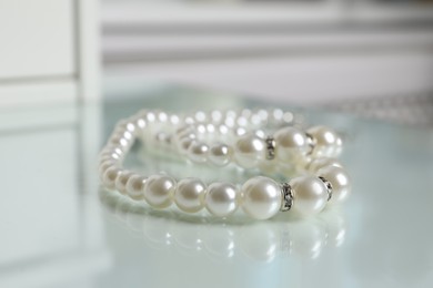 Elegant pearl necklace on white table, closeup