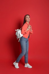 Photo of Beautiful young woman with stylish leather backpack on red background