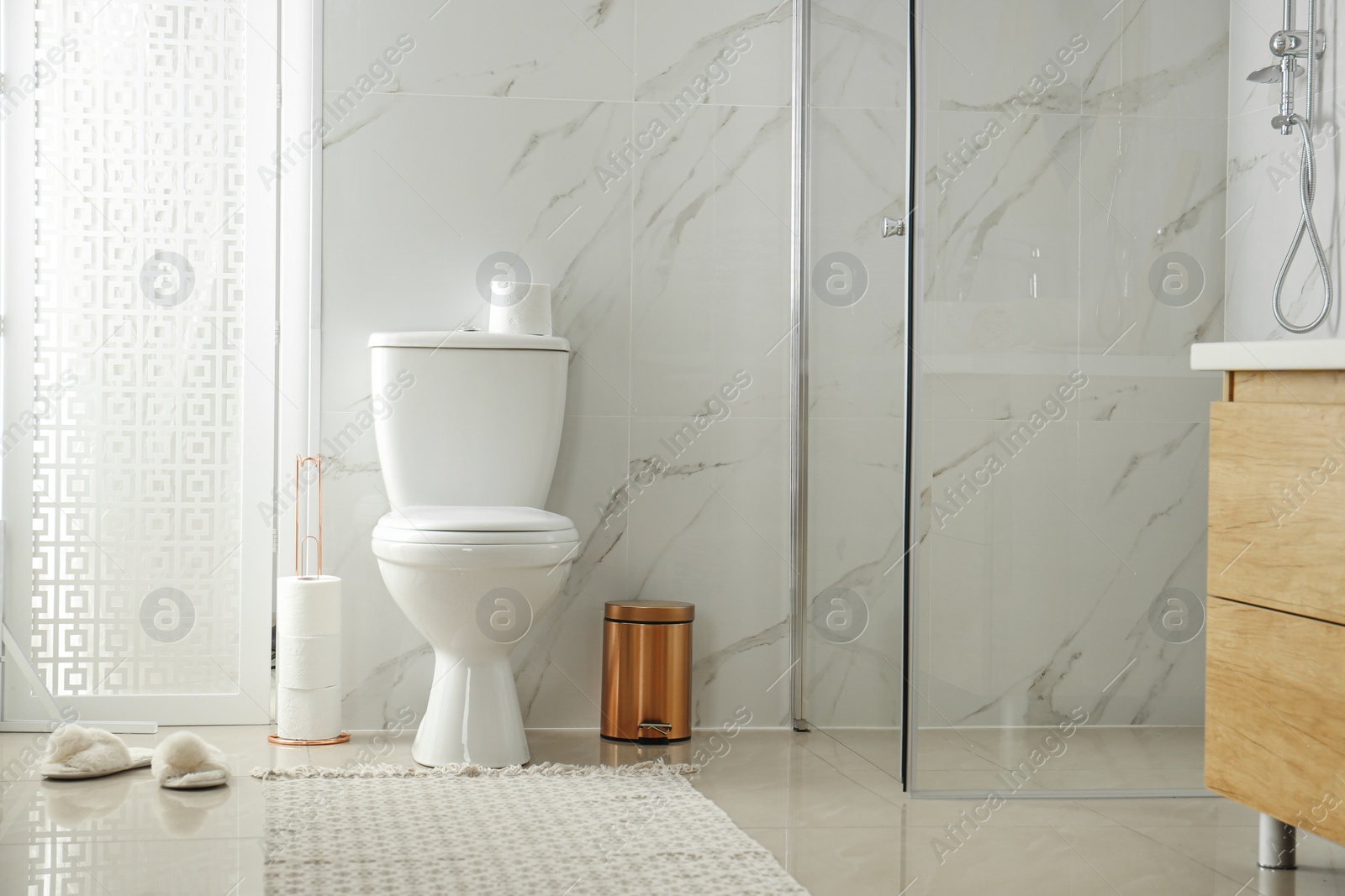 Photo of Toilet bowl near shower stall in modern bathroom interior