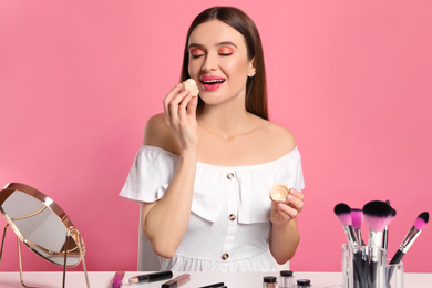 Photo of Beauty blogger applying lip balm on pink background