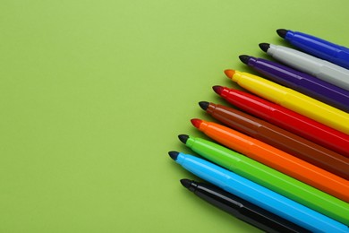 Photo of Many different colorful markers on light green background, above view. Space for text