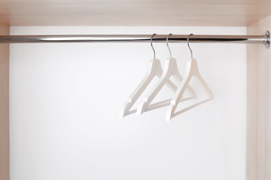 Photo of Clothes hangers on metal rail in wardrobe