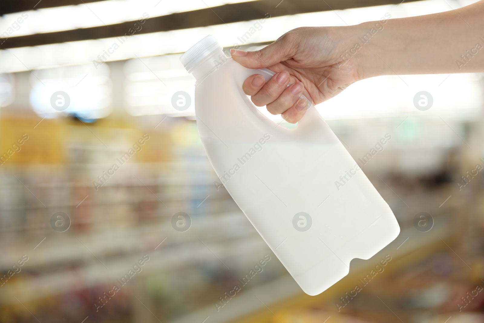 Image of Woman holding gallon bottle of milk in supermarket, closeup