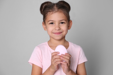 Photo of Cute little girl with soap bar on gray background