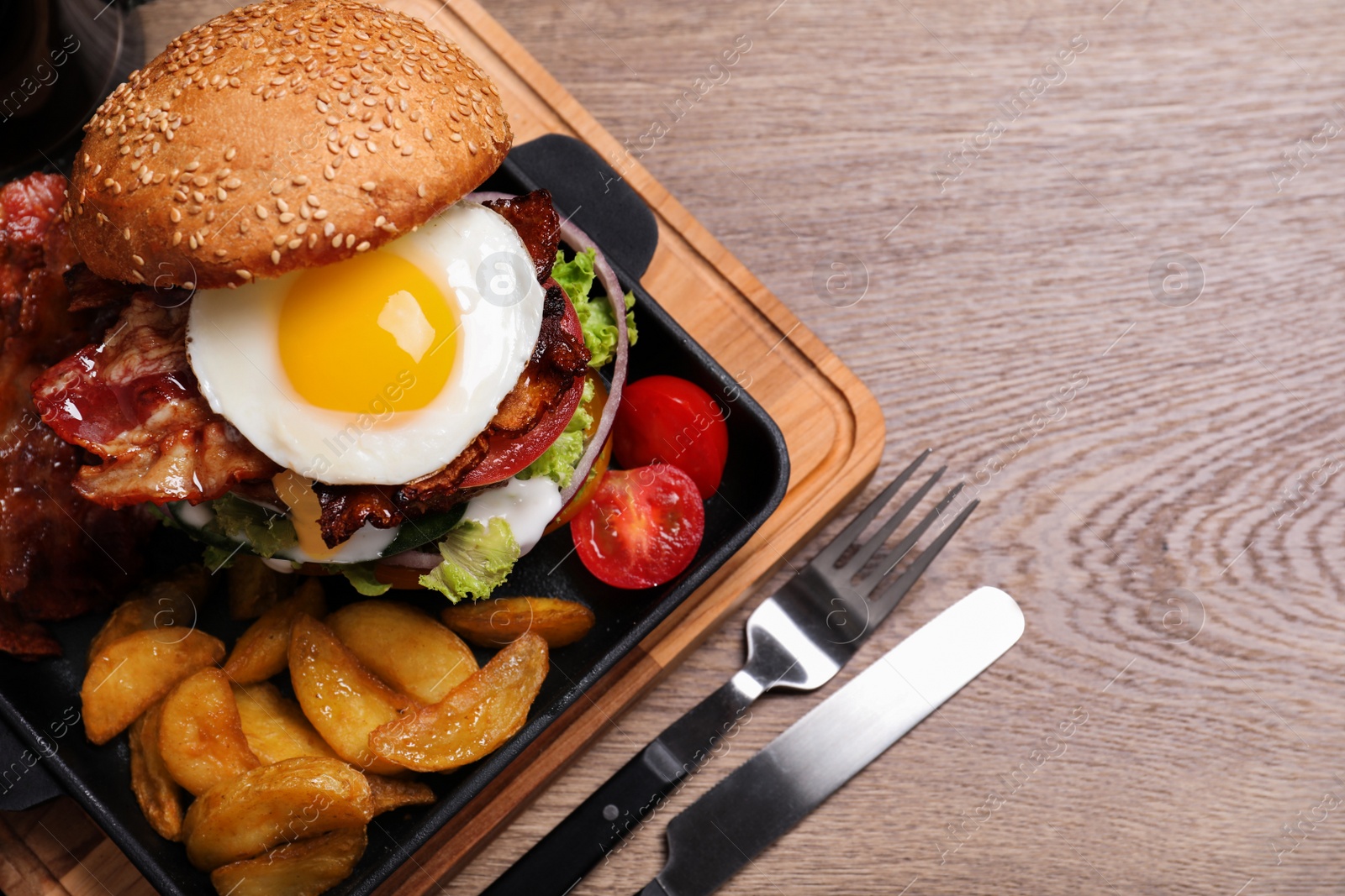 Photo of Fresh juicy bacon burger and fries on wooden table, flat lay. Space for text