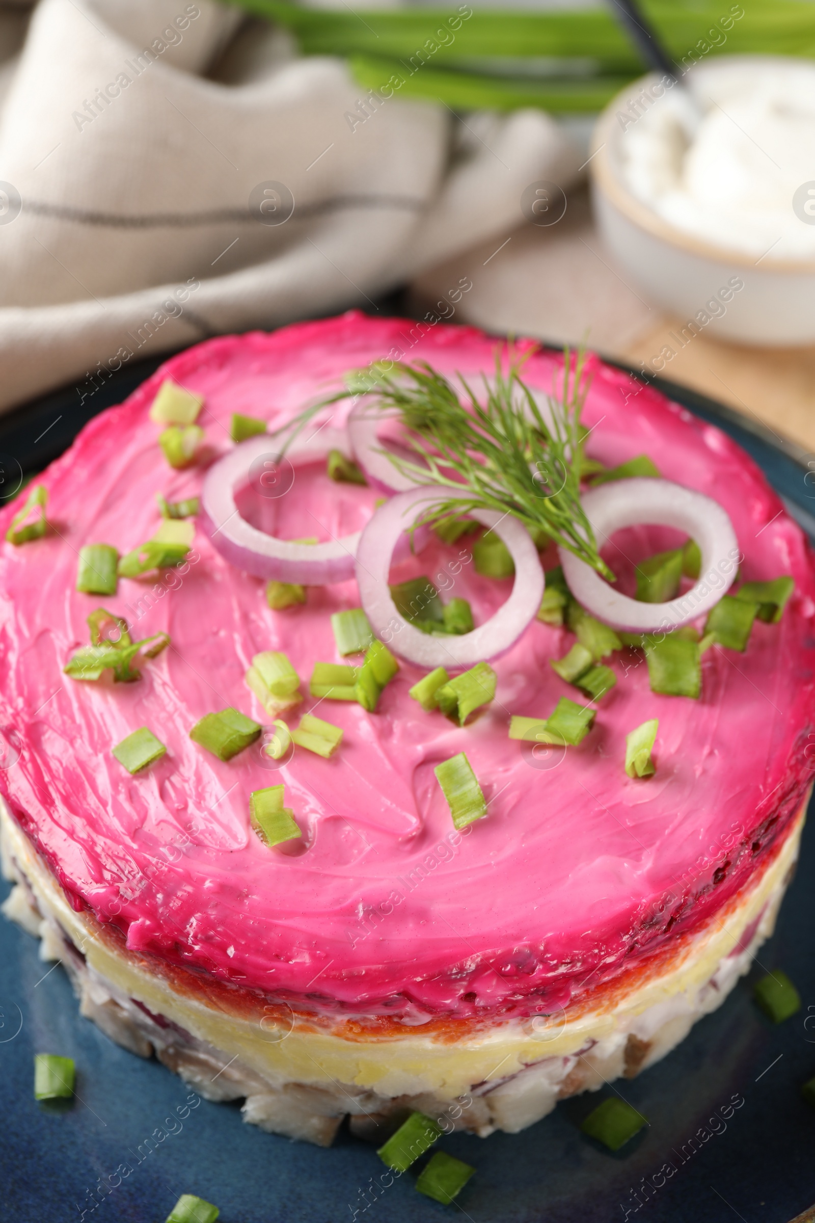 Photo of Herring under fur coat salad on blue plate, closeup. Traditional Russian dish