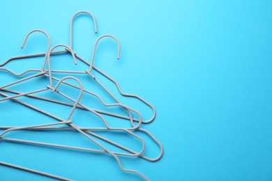 Photo of Hangers on light blue background, top view. Space for text