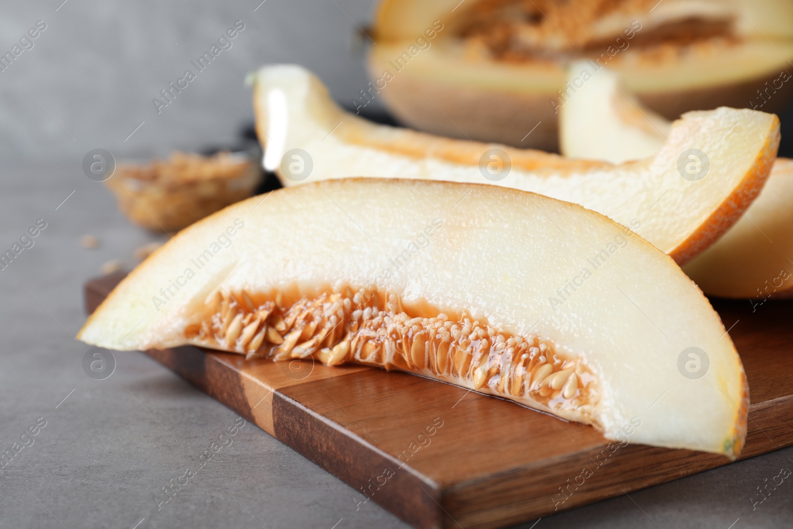 Photo of Slices of delicious honey melon on grey table, closeup