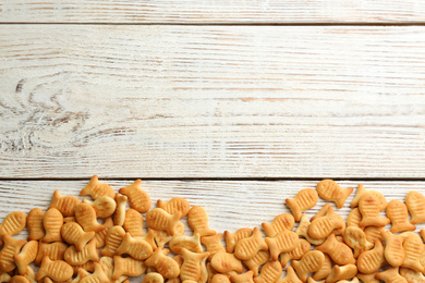 Delicious goldfish crackers on white wooden table, flat lay. Space for text