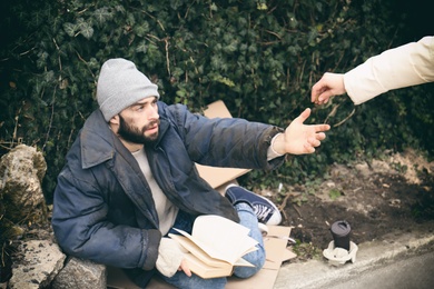 Photo of Woman giving alms to poor homeless man on street