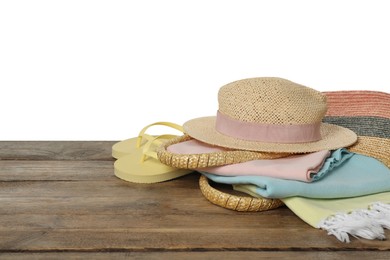 Beach bag with towel, hat and flip flops on wooden surface against white background. Space for text
