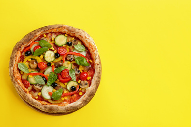 Photo of Delicious hot vegetable pizza on yellow background, top view. Space for text