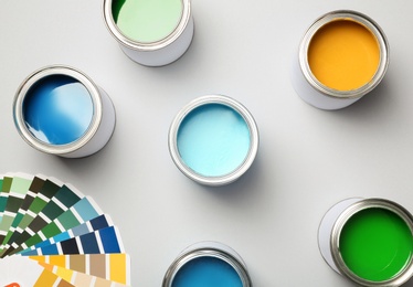Paint cans and color palette on white background, top view