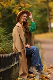 Portrait of beautiful woman sitting in autumn park